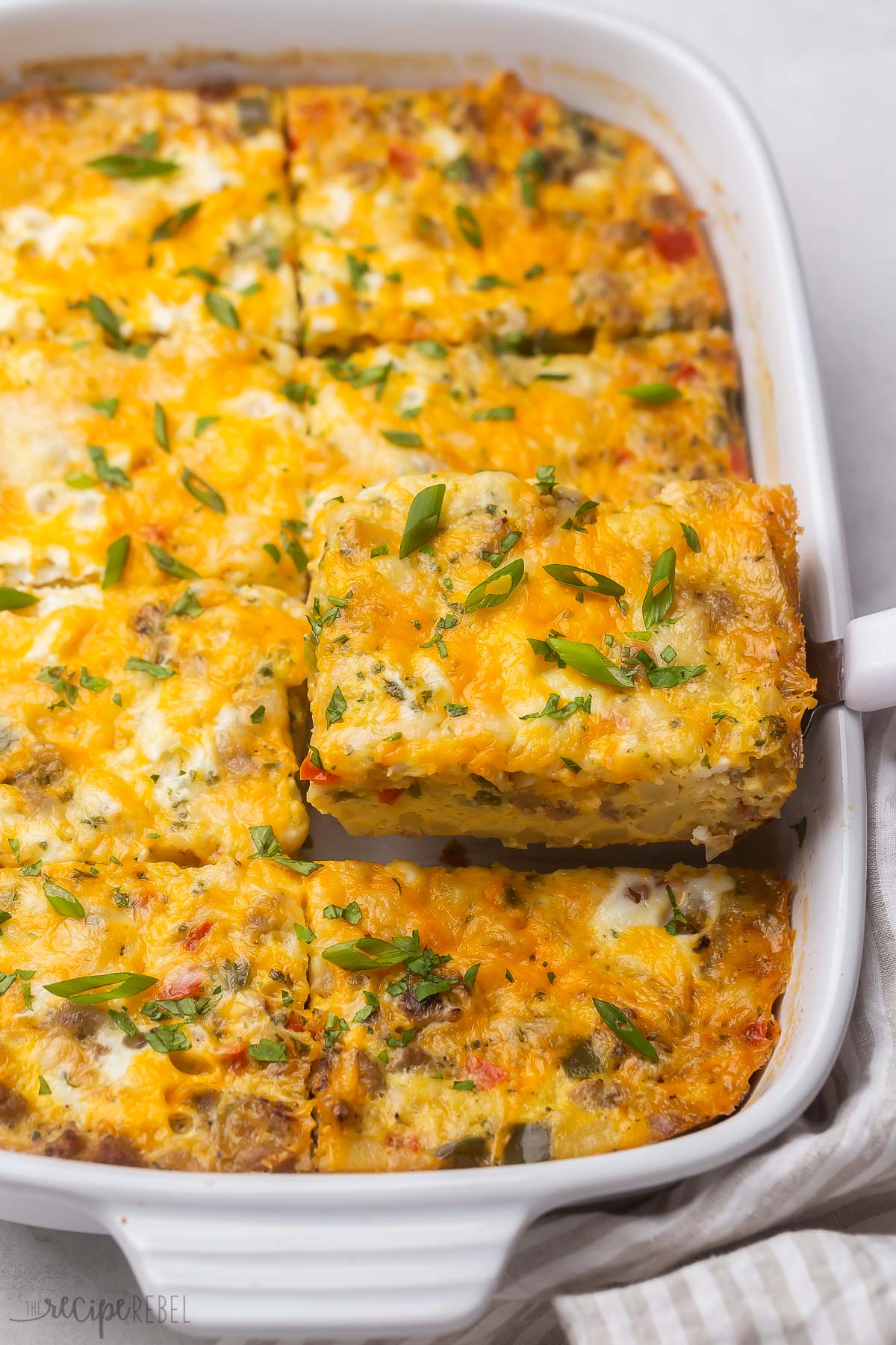 Top view of hashbrown breakfast casserole in white dish with a piece being lifted out.