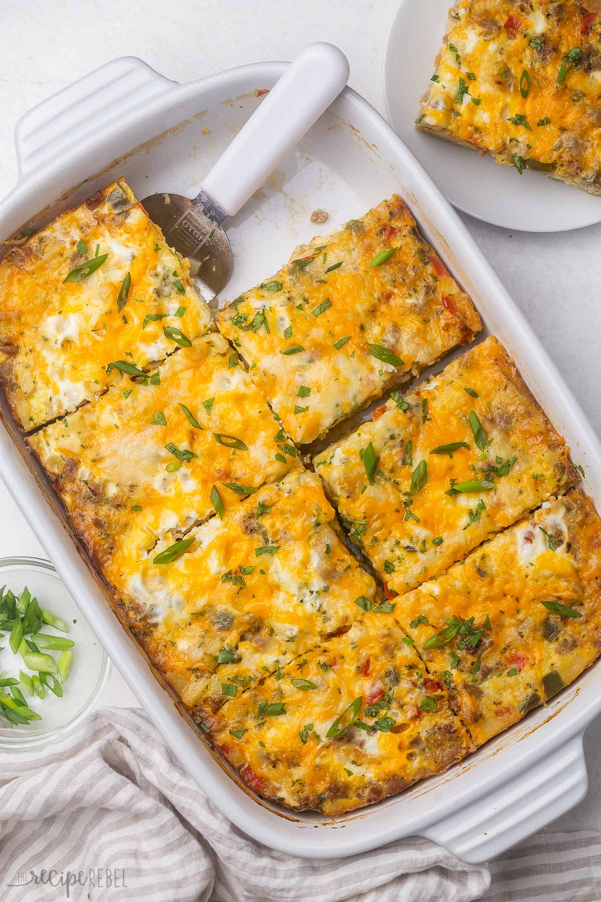 overhead view of breakfast casserole in white baking dish with a piece out.