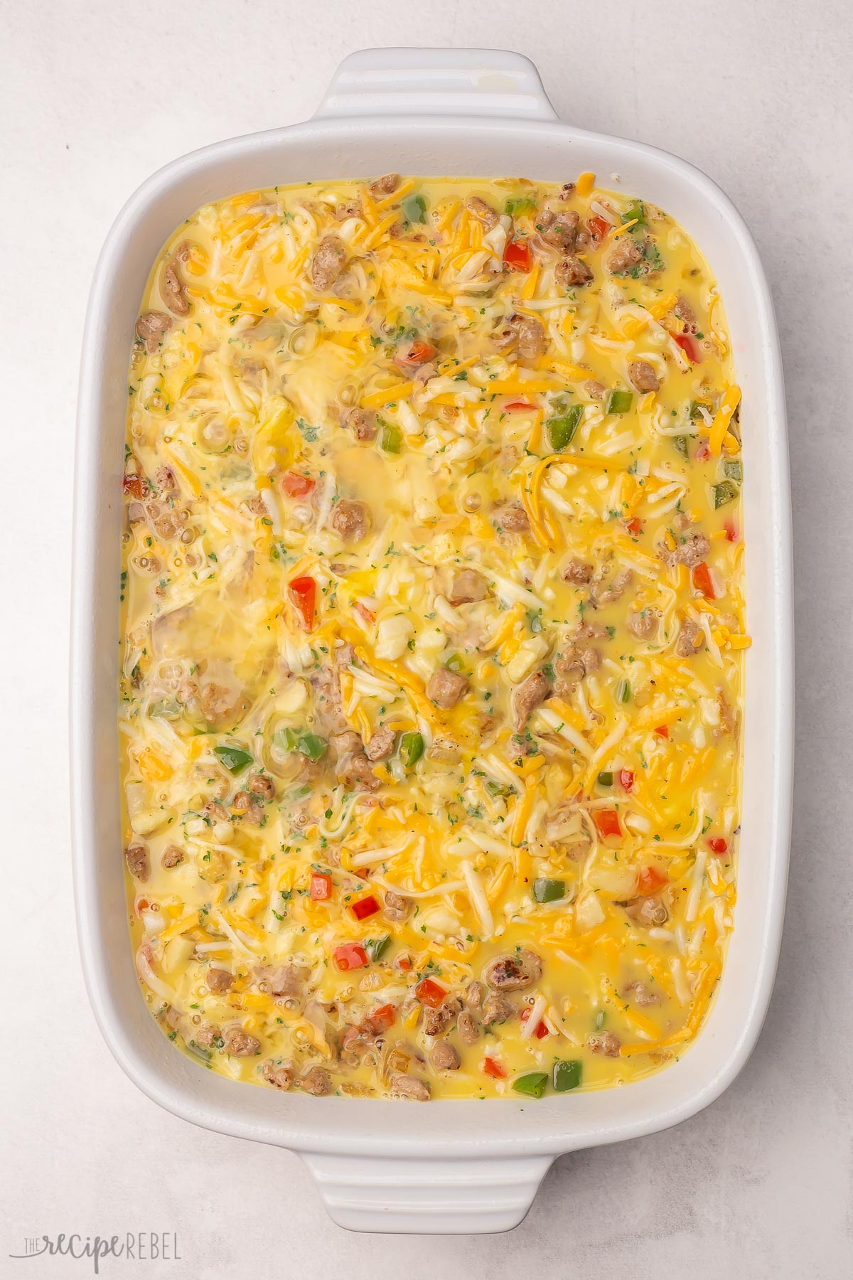 white baking dish filled with hashbrown breakfast casserole ingredients.