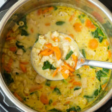 metal ladle scooping chicken noodle soup from instant pot.