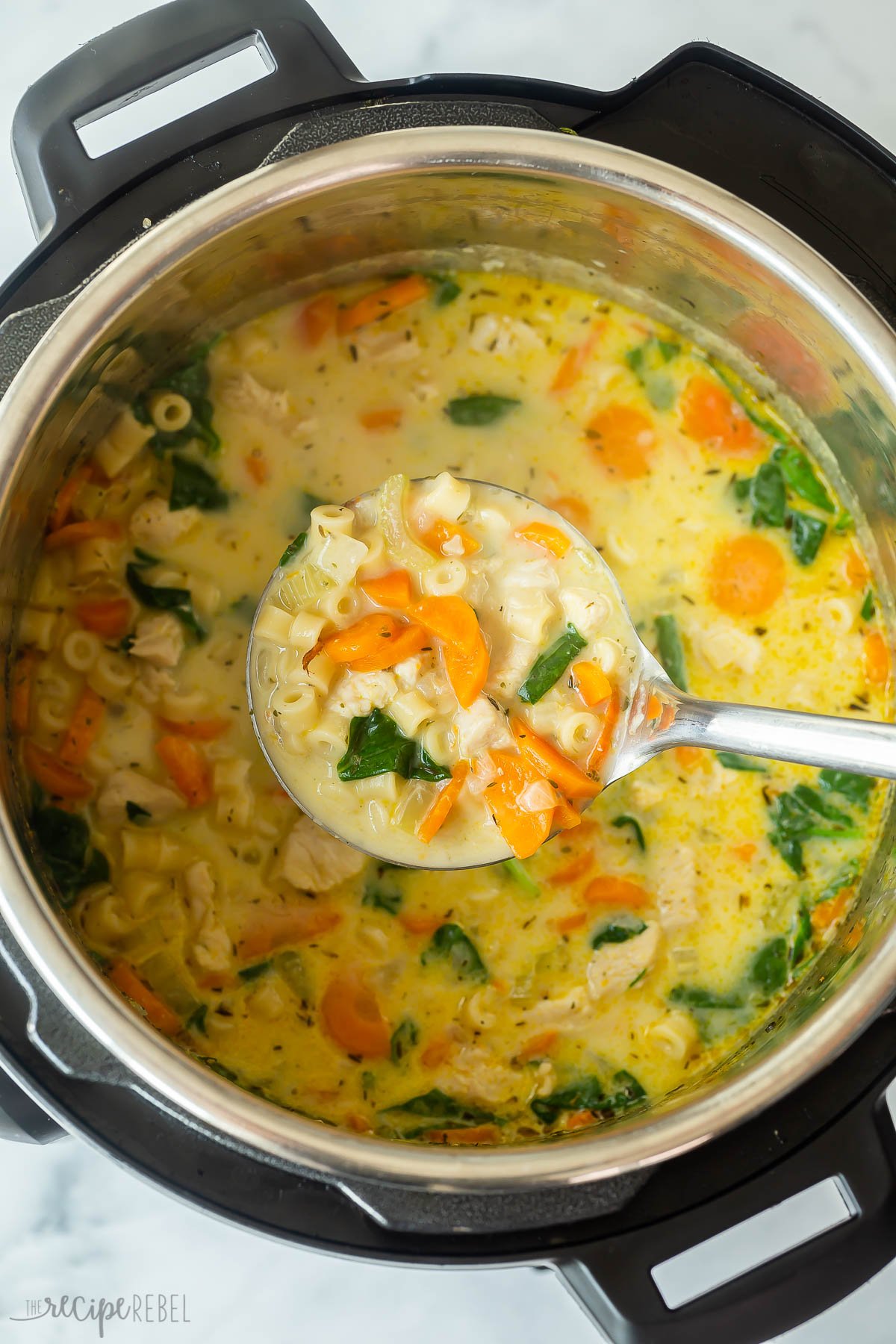 metal ladle scooping chicken noodle soup from instant pot.