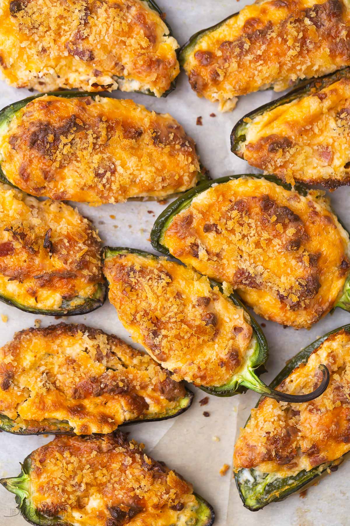 These Jalapeño Poppers are one of my favorite appetizers! They're perfectly spicy and layered with a creamy filling, salty bacon, and crispy Panko. #appetizer #recipe | appetizers | appetizer recipe | finger food | party food | game day close up of jalapeno poppers on parchment paper.