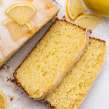 loaf of lemon bread with two pieces sliced on grey surface.