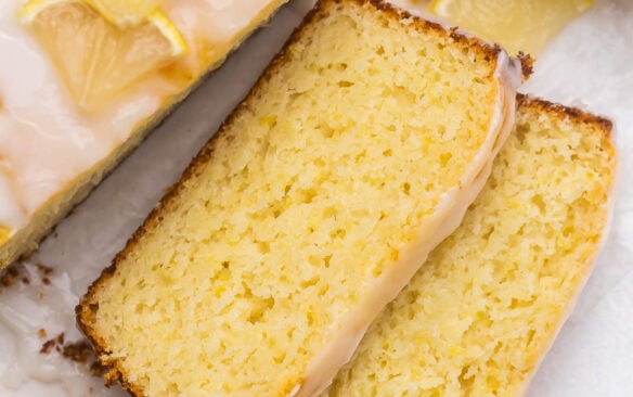 loaf of lemon bread with two pieces sliced on grey surface.