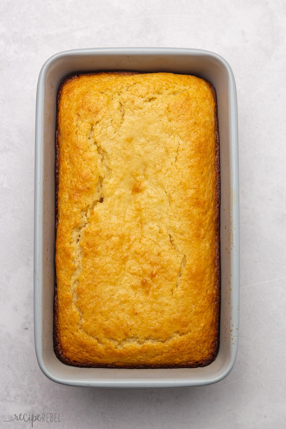 Overhead view of a pan of baked lemon bread on a grey surface.