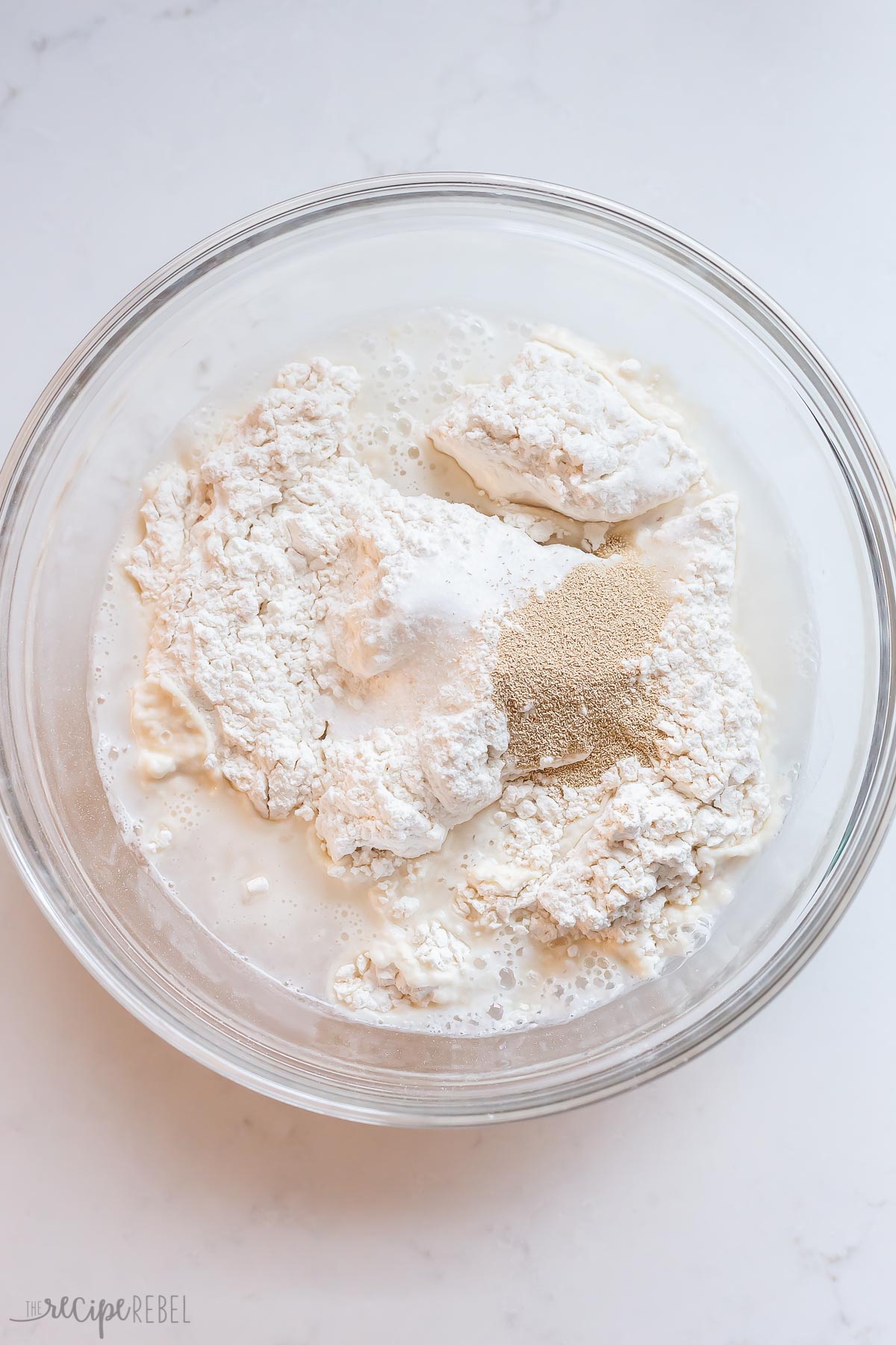 unmixed ingredients for no knead bread in a glass bowl.