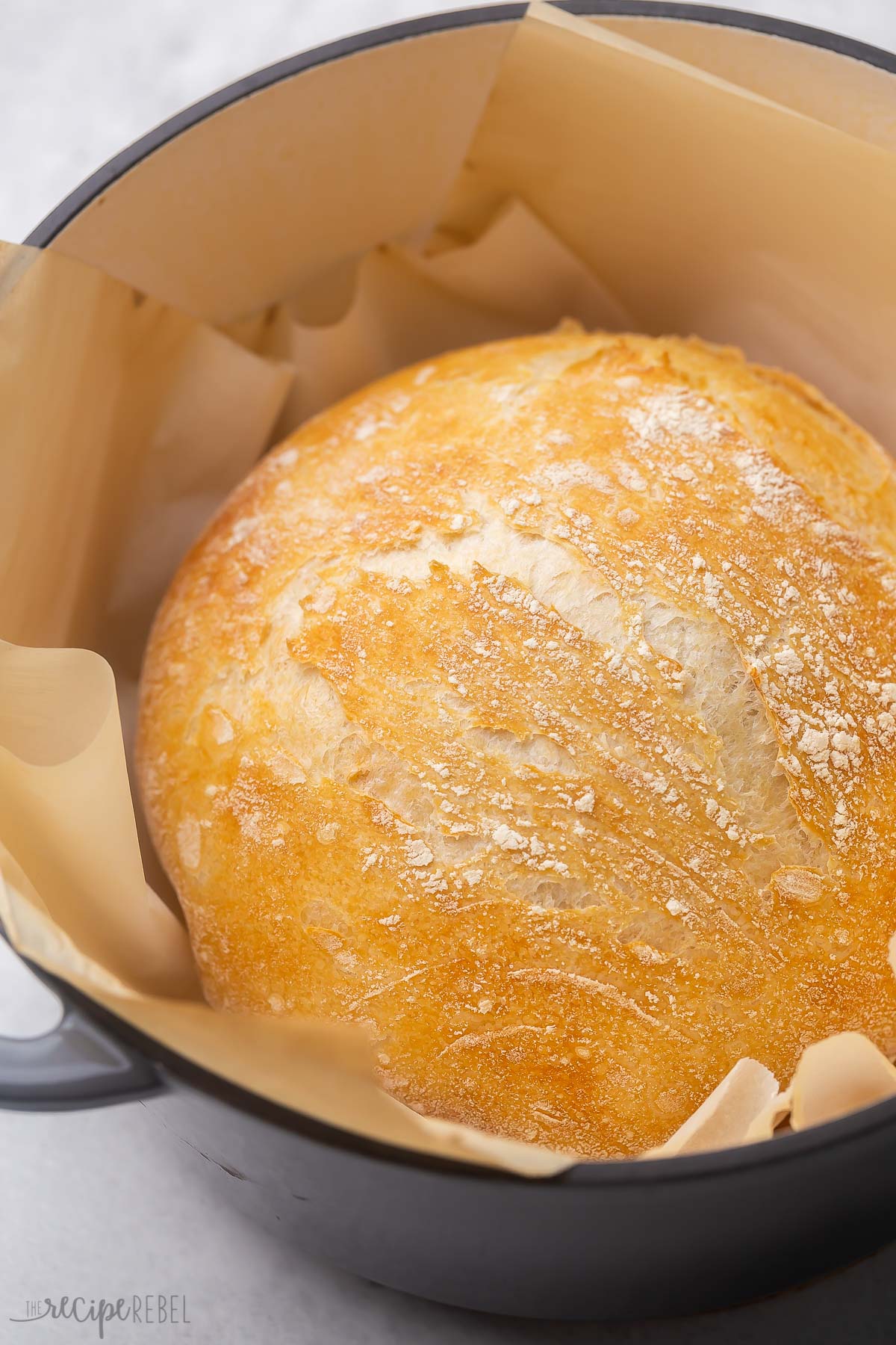 Top view of a golden loaf of no knead bread in a black dutch oven.