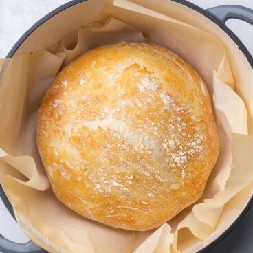 top view of a full loaf of no knead bread sitting in a dutch oven.