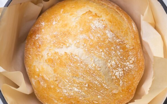 top view of a full loaf of no knead bread sitting in a dutch oven.