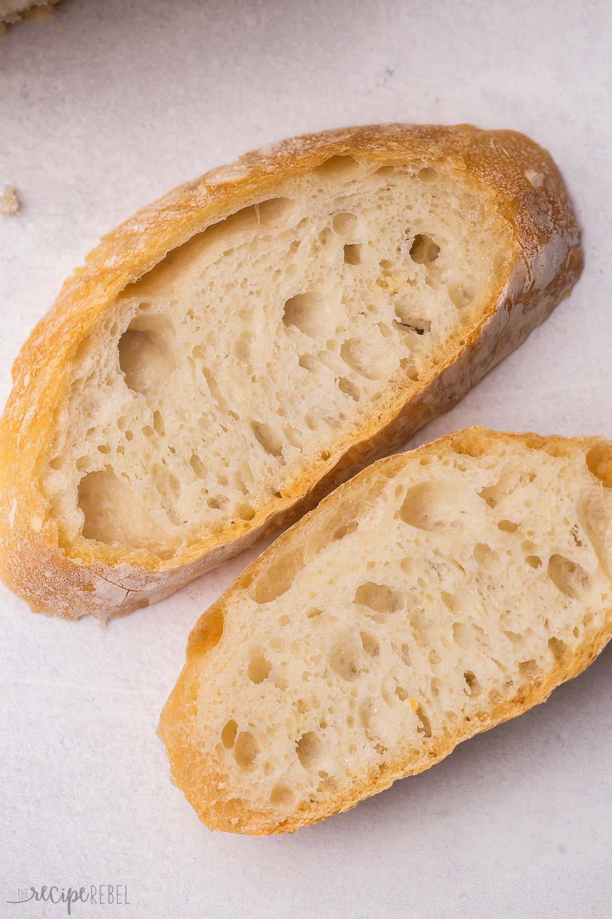 Close up overhead shot of two slices of no knead bread on grey background.