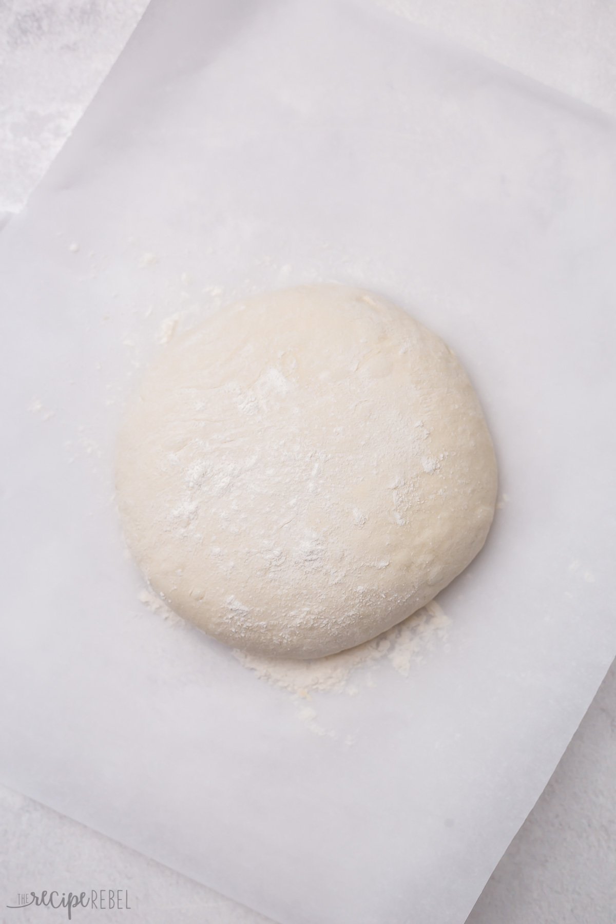 smooth ball of dough lying on a piece of parchment paper.