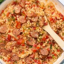 overhead shot of cooked one pan sausage and rice with wooden ladle.