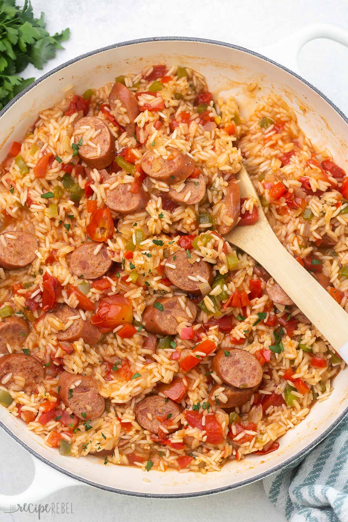 overhead shot of cooked one pan sausage and rice with wooden ladle.