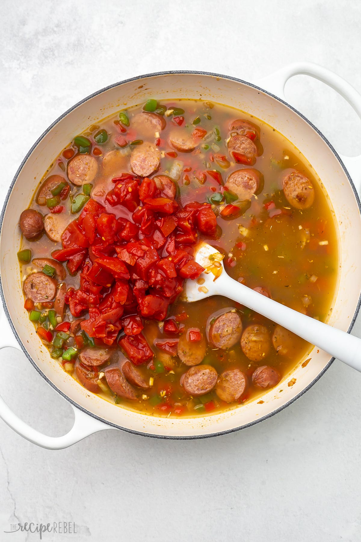 top view of one pot sausage and rice ingredients in white pot.