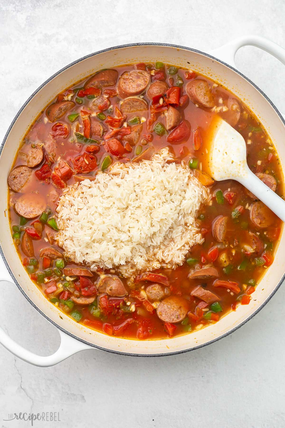 full pot of ingredients for one pot sausage and rice with rice on top.