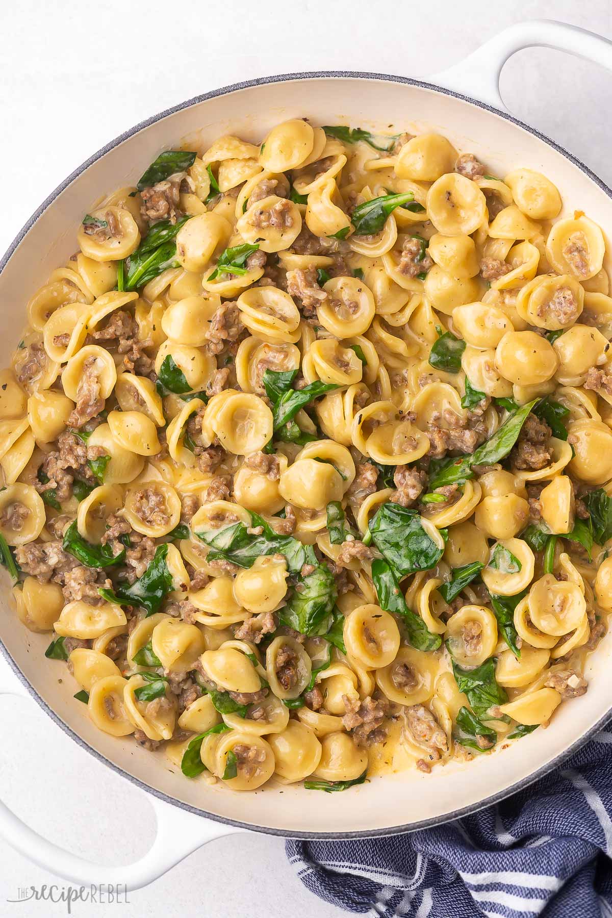 overhead view of orecchiette pasta and sausage in white pot.