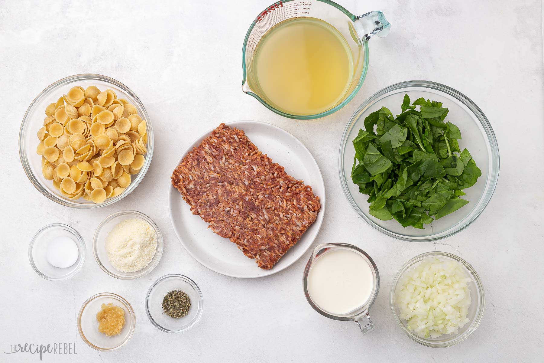 overhead shot of orecchiette pasta with sausage ingredients on grey surface.