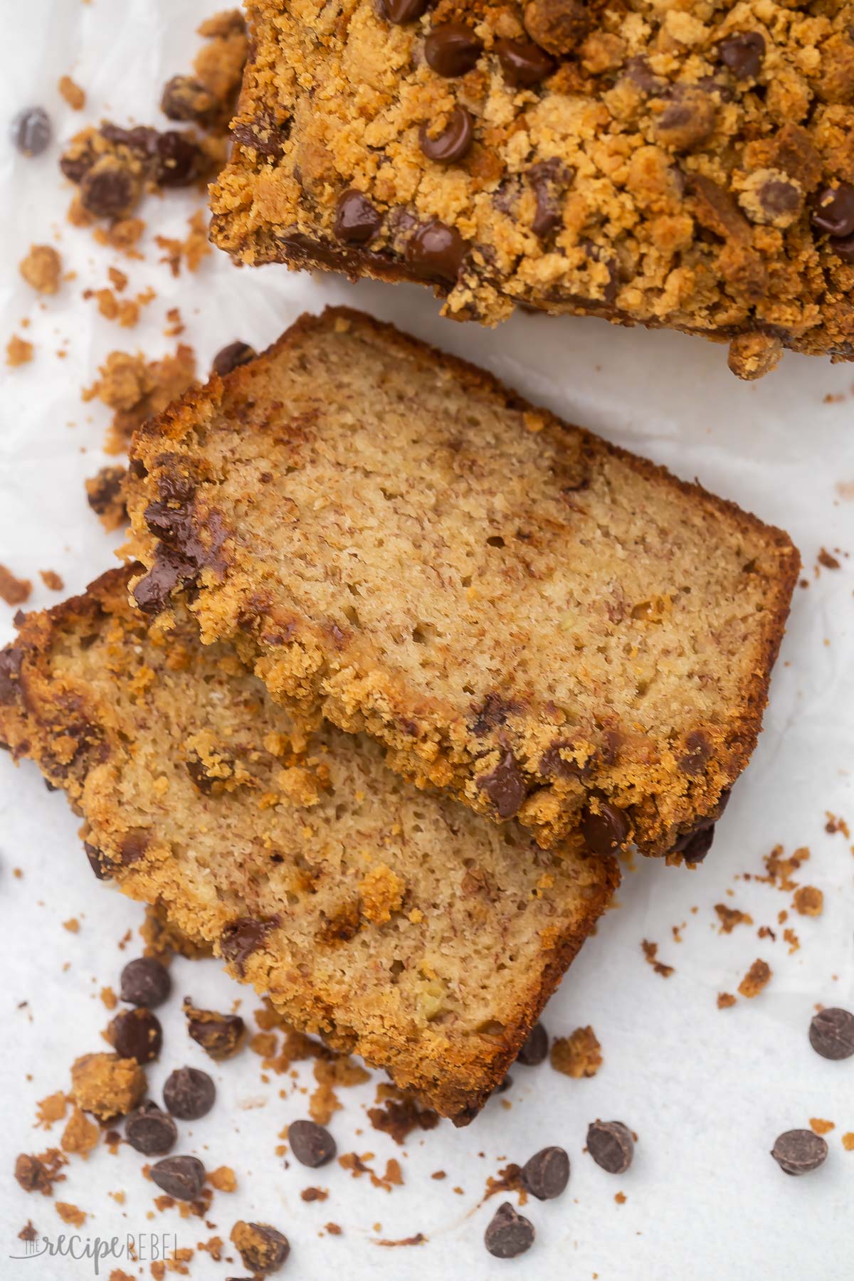 close up of sliced peanut butter chocolate chip streusel banana bread on grey surface.