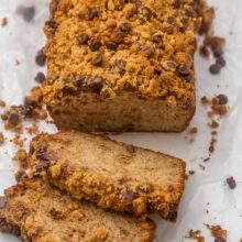 loaf of peanut butter chocolate chip streusel banana bread with two slices lying in front.