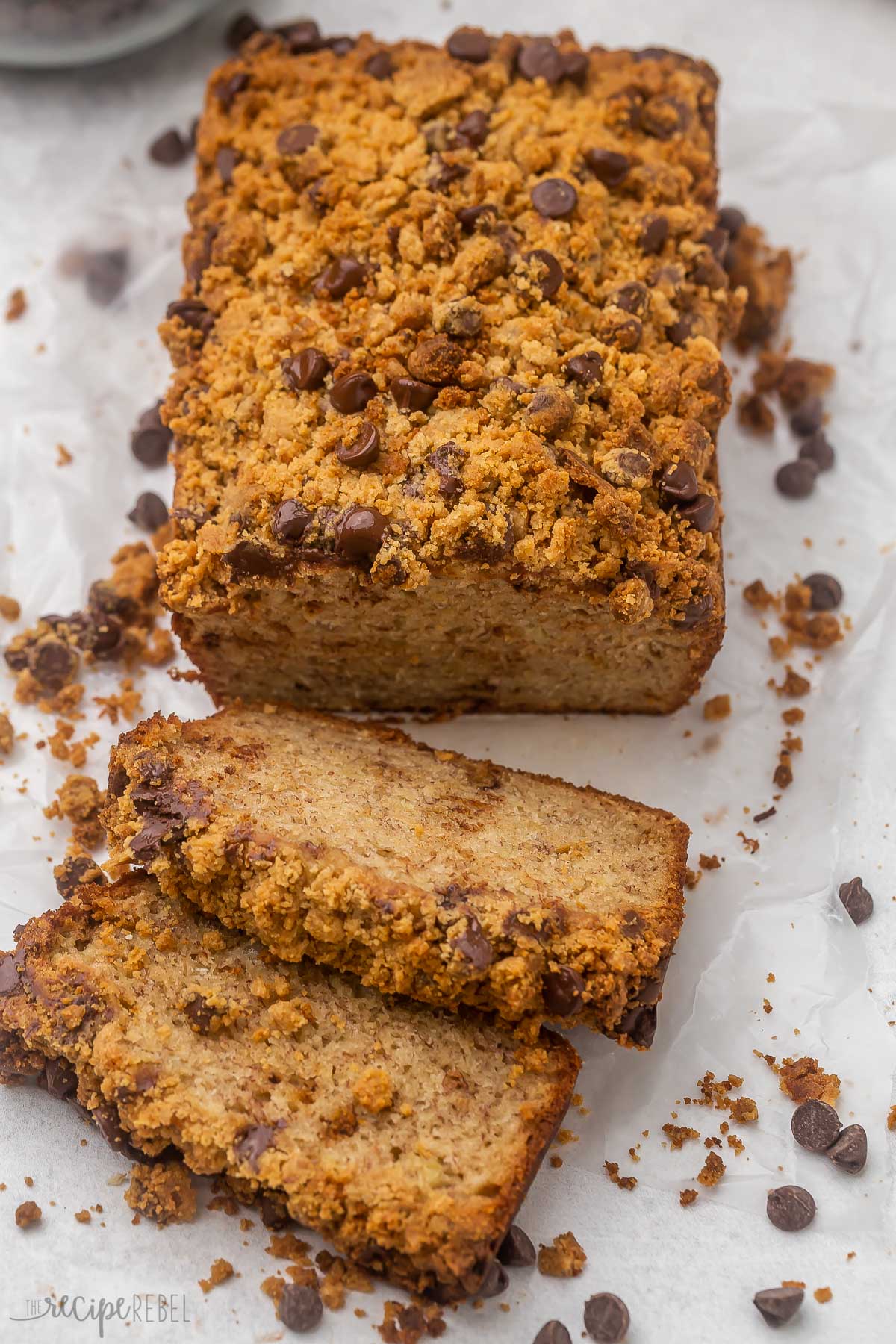 loaf of peanut butter chocolate chip streusel banana bread with two slices lying in front.