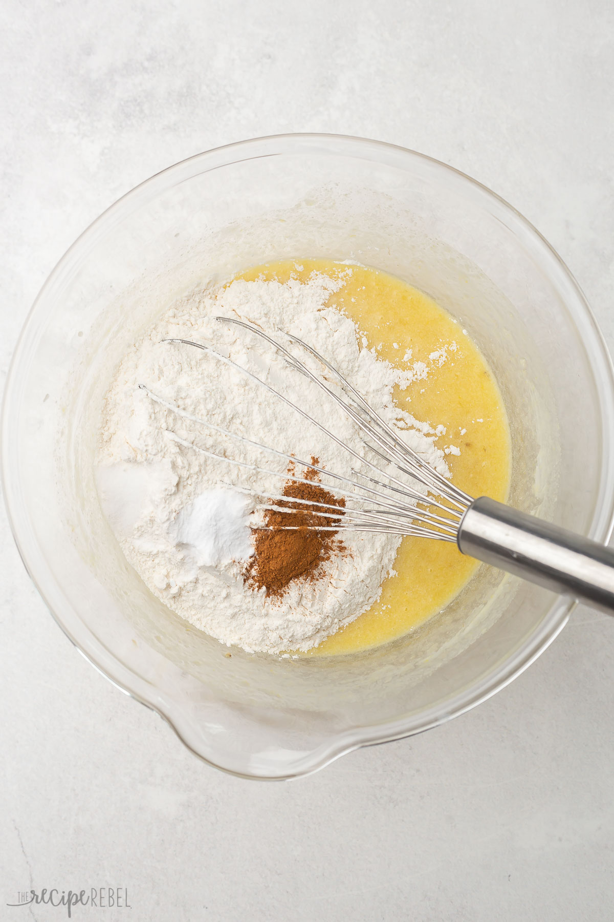 glass bowl with unmixed wet and dry ingredients and steel whisk.