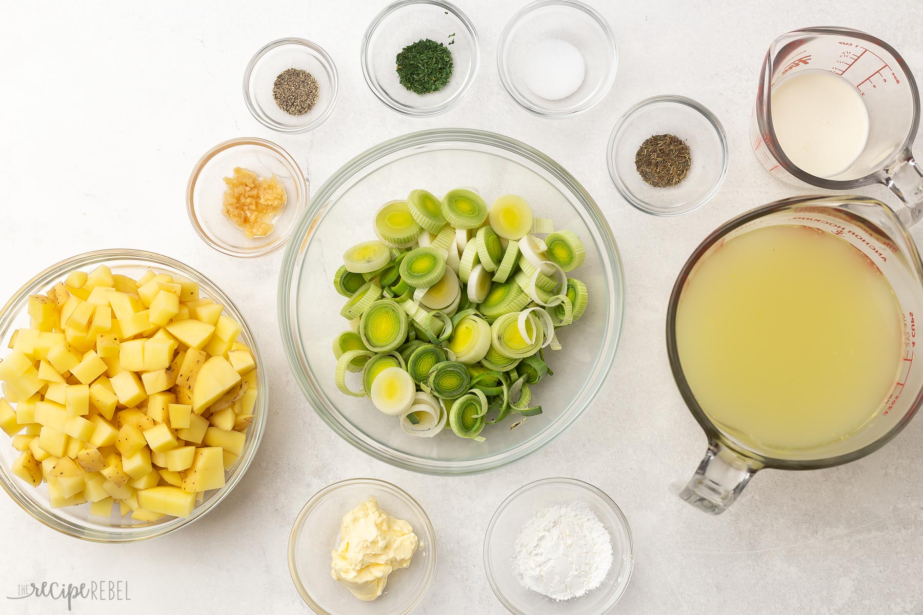 Overhead view of potato leek soup ingredients in glass bowls.