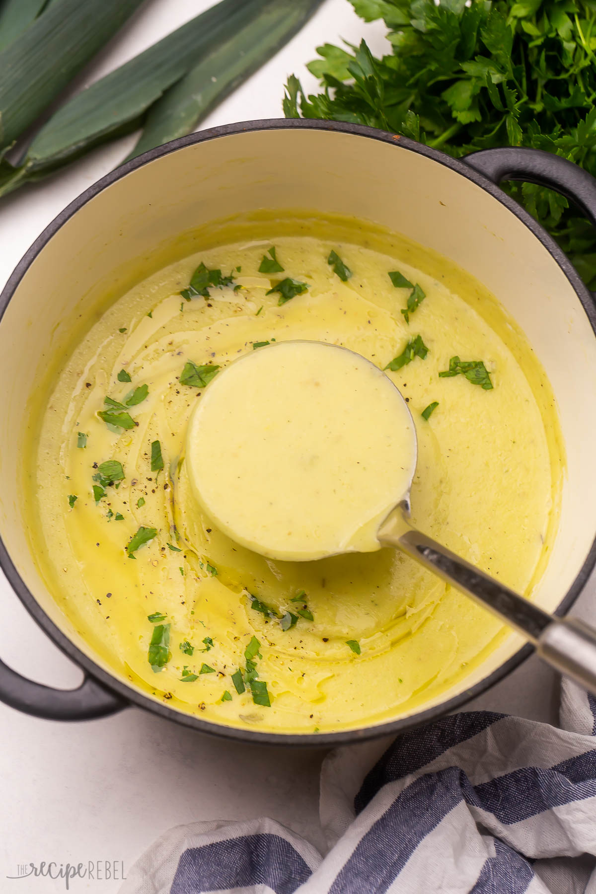 a full ladle of potato leek soup coming out of large pot.
