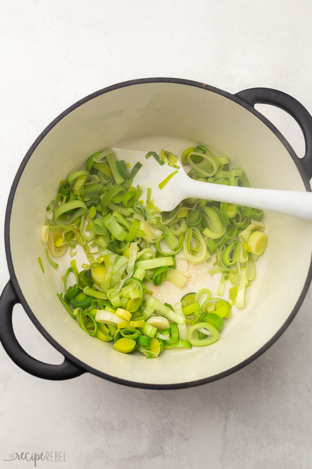 a large pot with a spatula and chopped leeks inside.