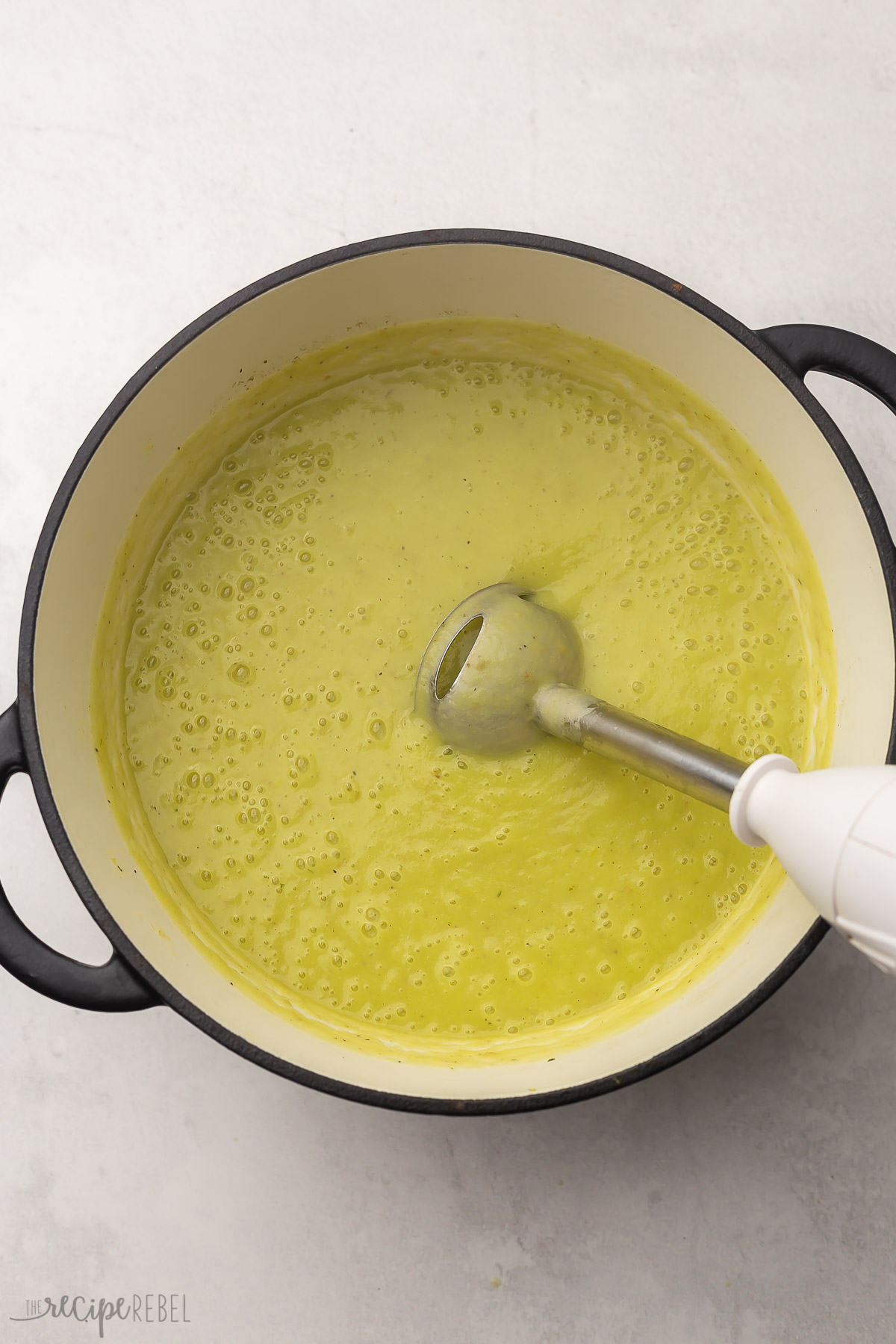 immersion blender in a pot of green pureed potato leek soup.