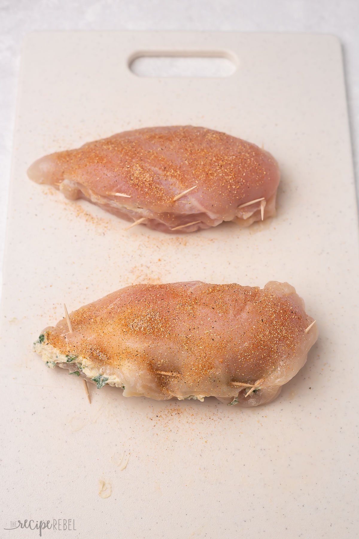two chicken breasts stuffed, seasoned, and held closed with toothpicks.