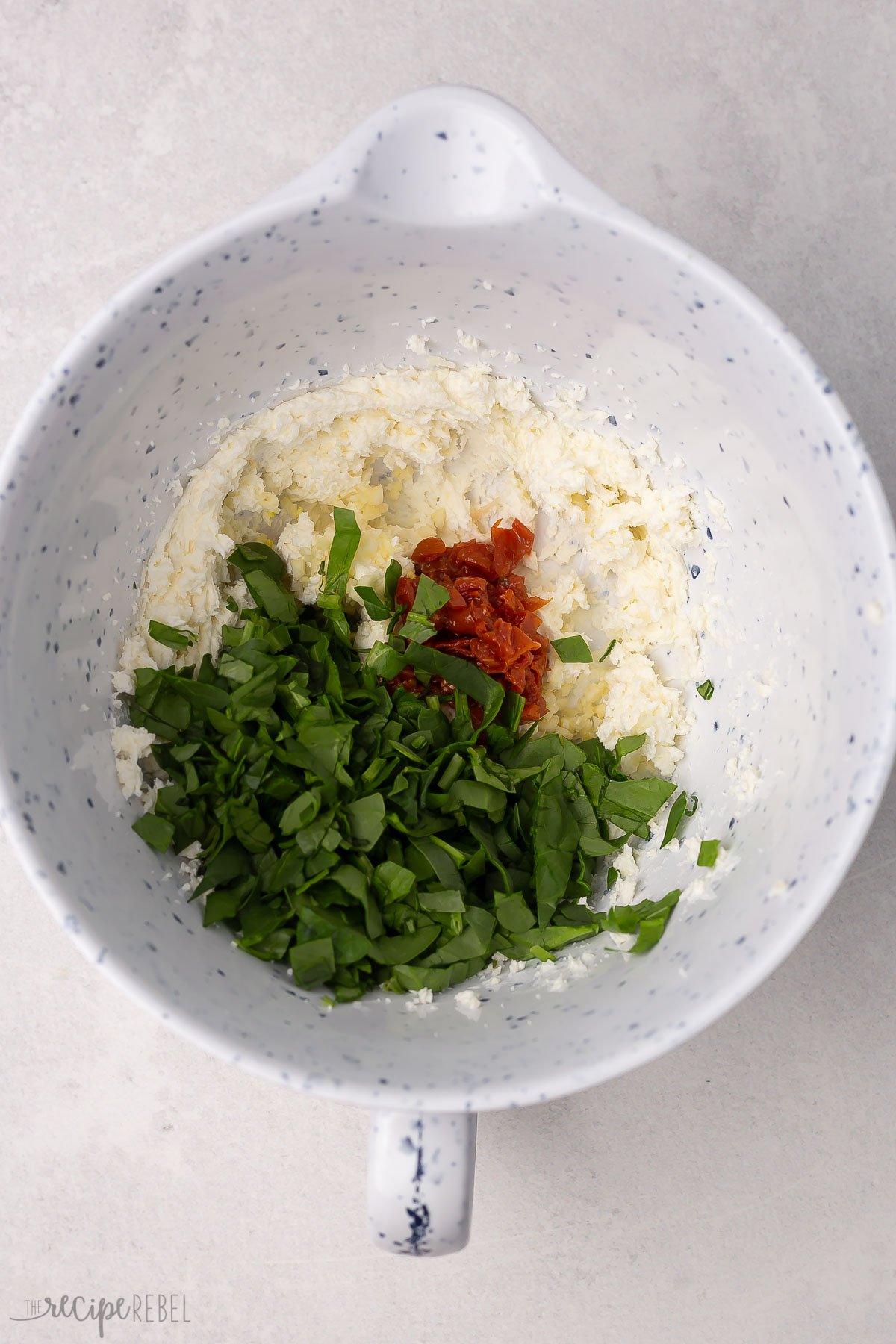 mixing bowl with spinach and other ingredients not yet mixed.