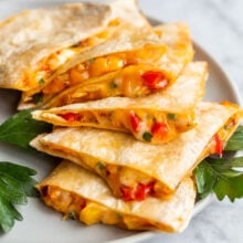 Close up photo of cheesy quesadillas slices on a plate on a grey plate.