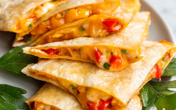 Close up photo of cheesy quesadillas slices on a plate on a grey plate.