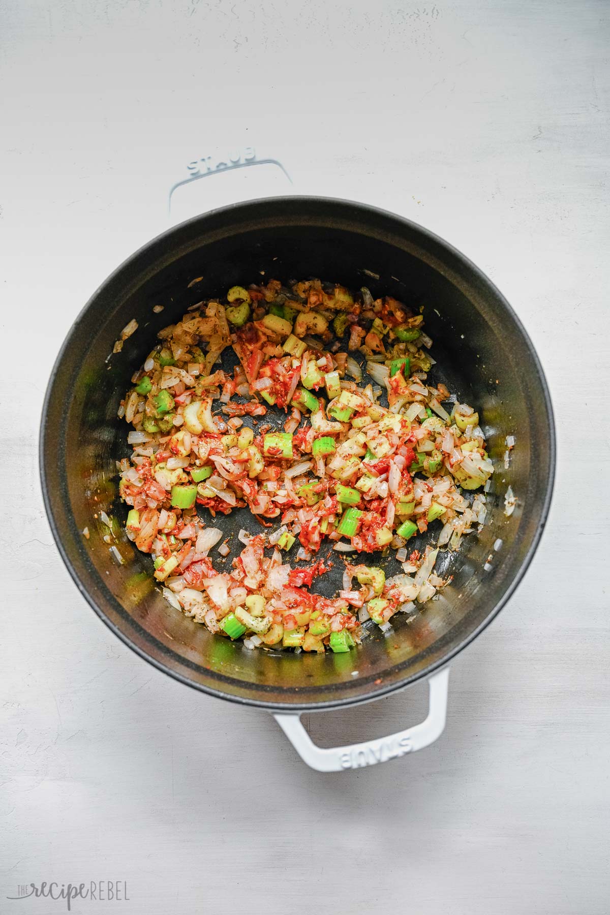 vegetables tomato paste and seasonings added to onion in soup pot.