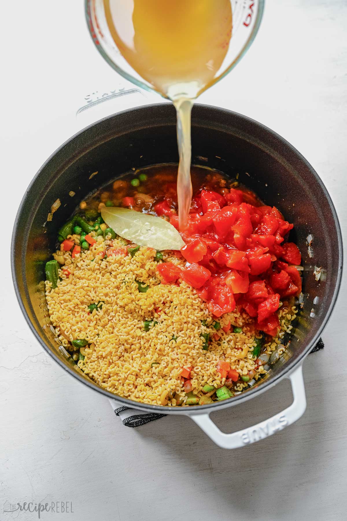 alphabet noodles tomatoes and broth added to soup pot.