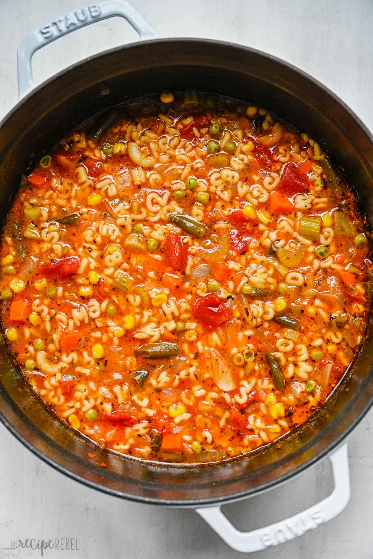 close up image of alphabet soup in pot on white background.