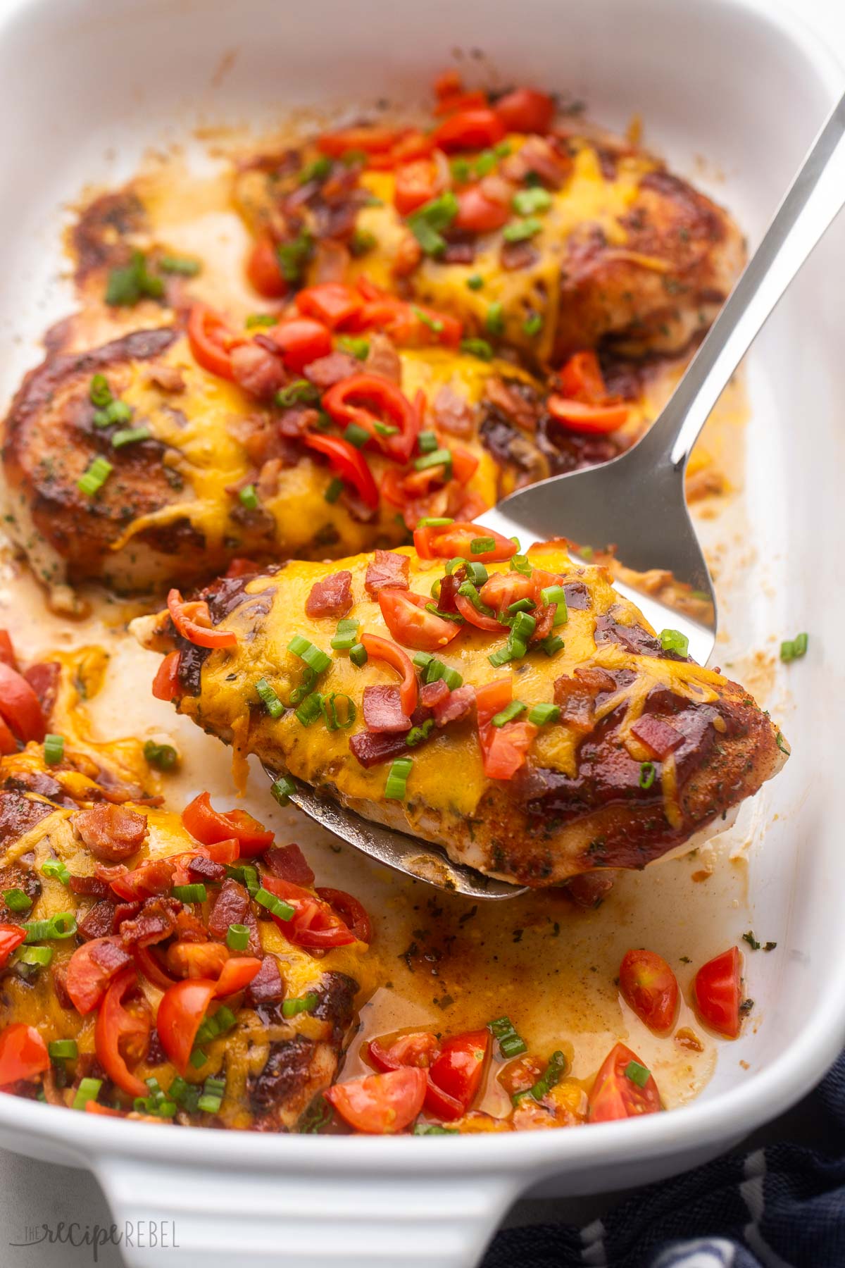 white pan with spatula lifting baked monterey chicken breast.