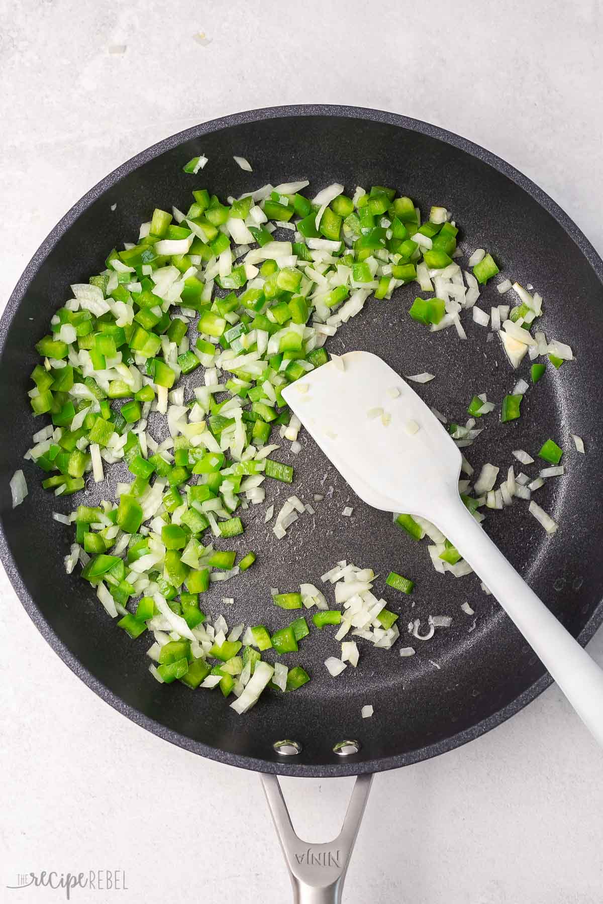 peppers and onions in black frying pan.
