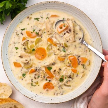 Top view of chicken wild wice soup in a white bowl with a spoon in it.