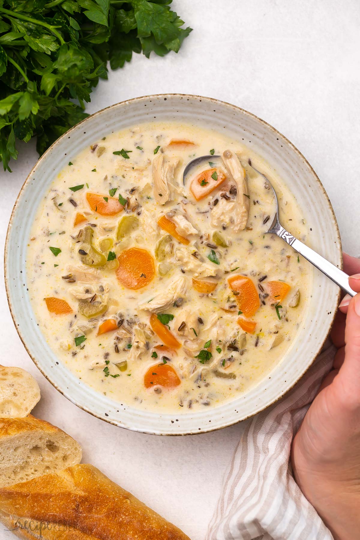 Top view of chicken wild wice soup in a white bowl with a spoon in it. 