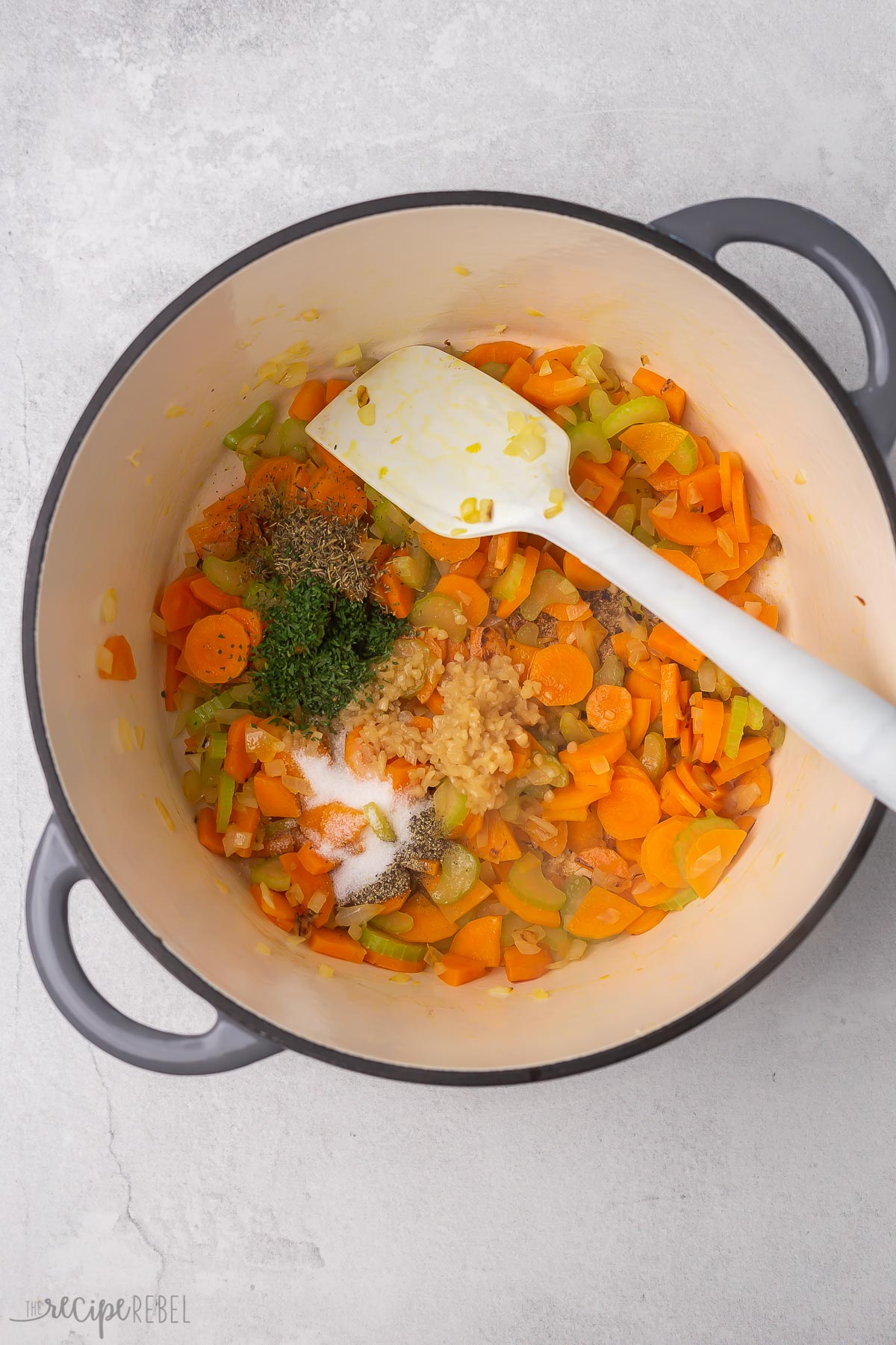 Top view of dutch oven with vegetables being sauteed with seasoning.. 