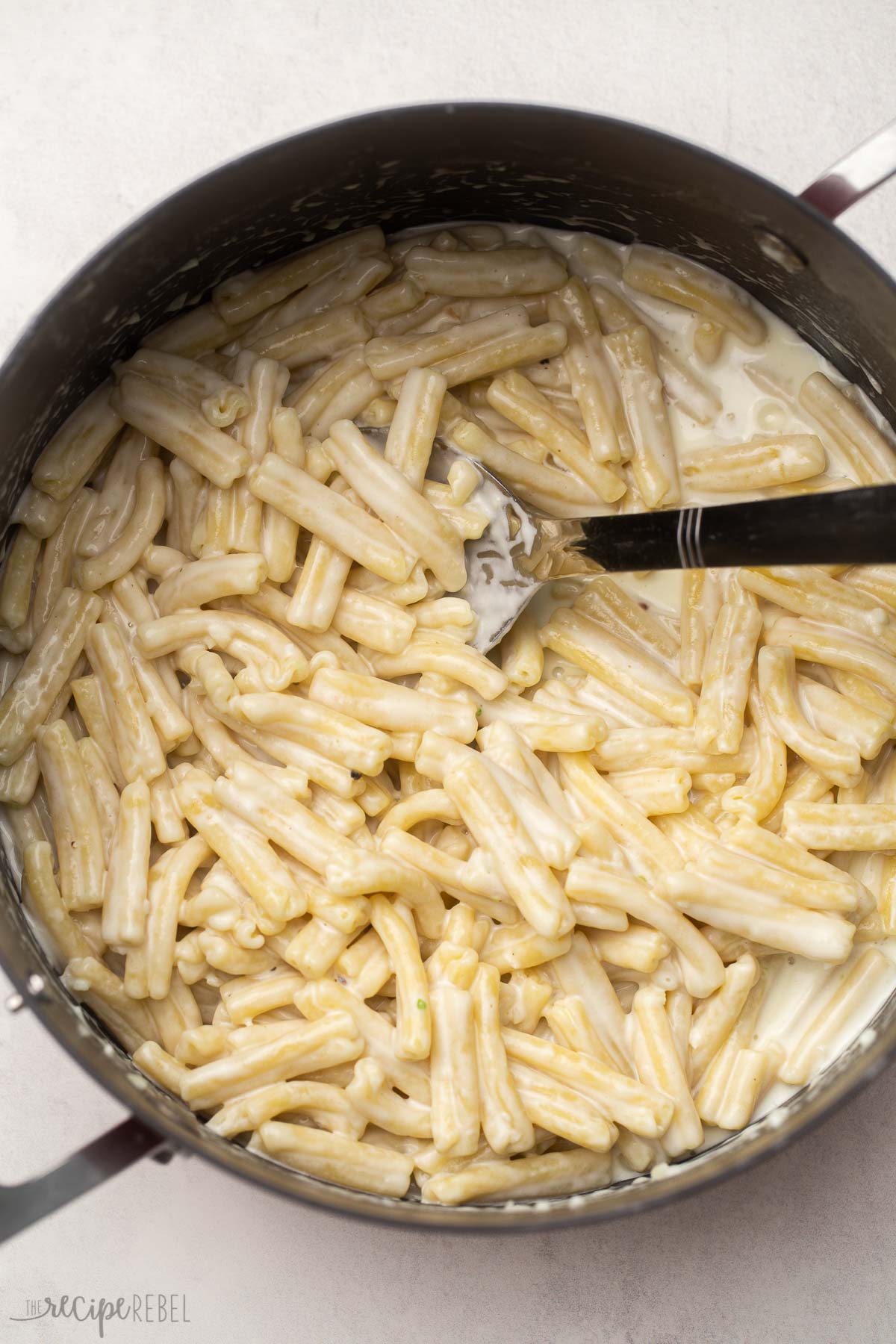 full pot of prepared pasta with steel scoop.