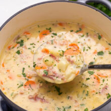 Top view of a big pot filled with ham and potato soup with a ladle in it.