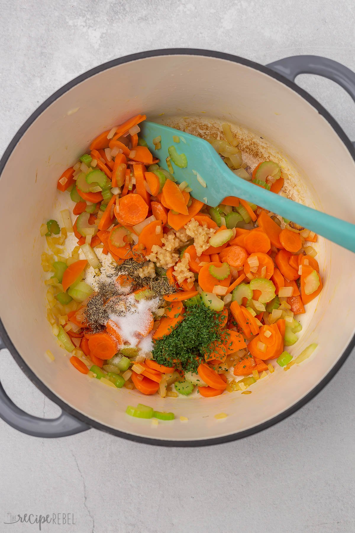 vegetables and seasonings in a grey dutch oven.