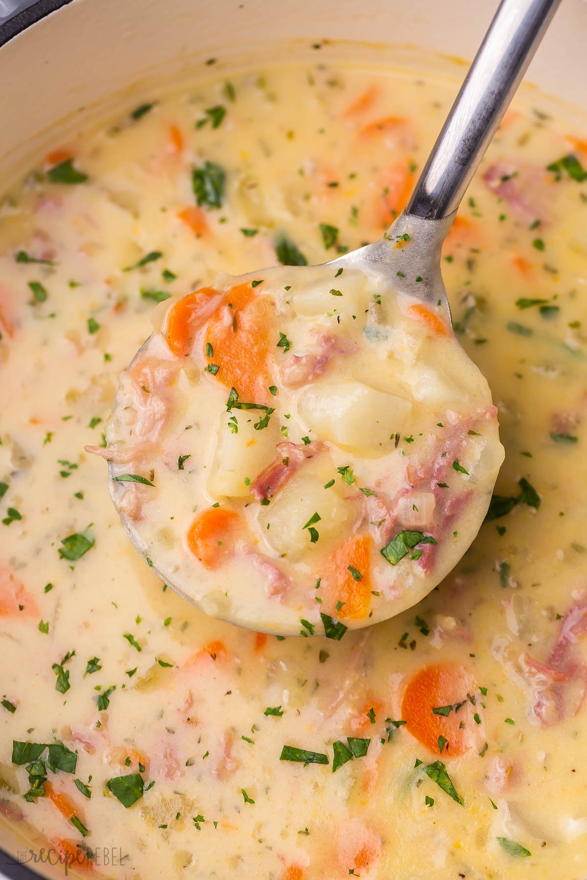 Top view close up of ham and potato soup with a ladle lifting some out. 