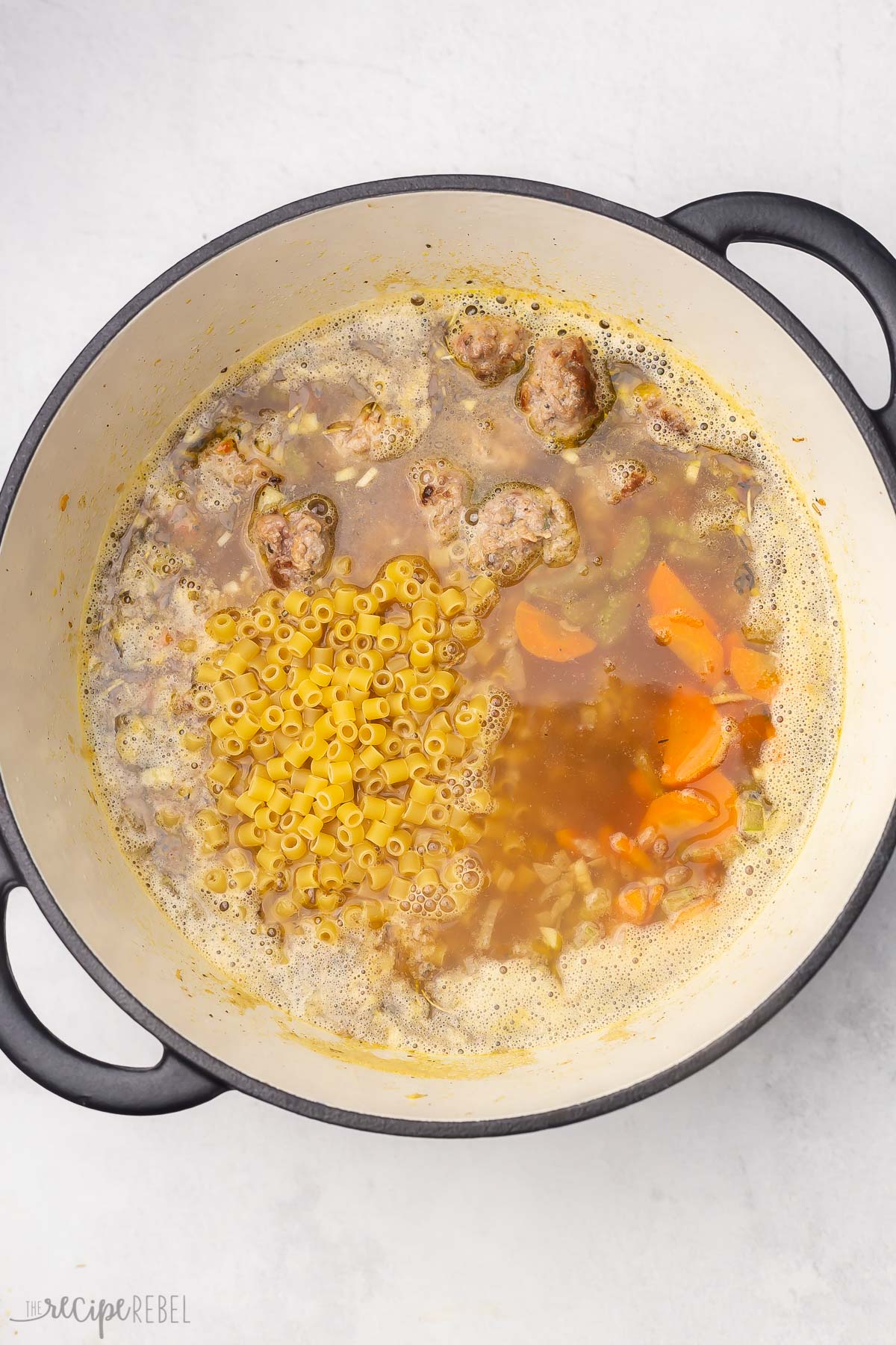 dutch oven with pasta on top of other soup ingredients.