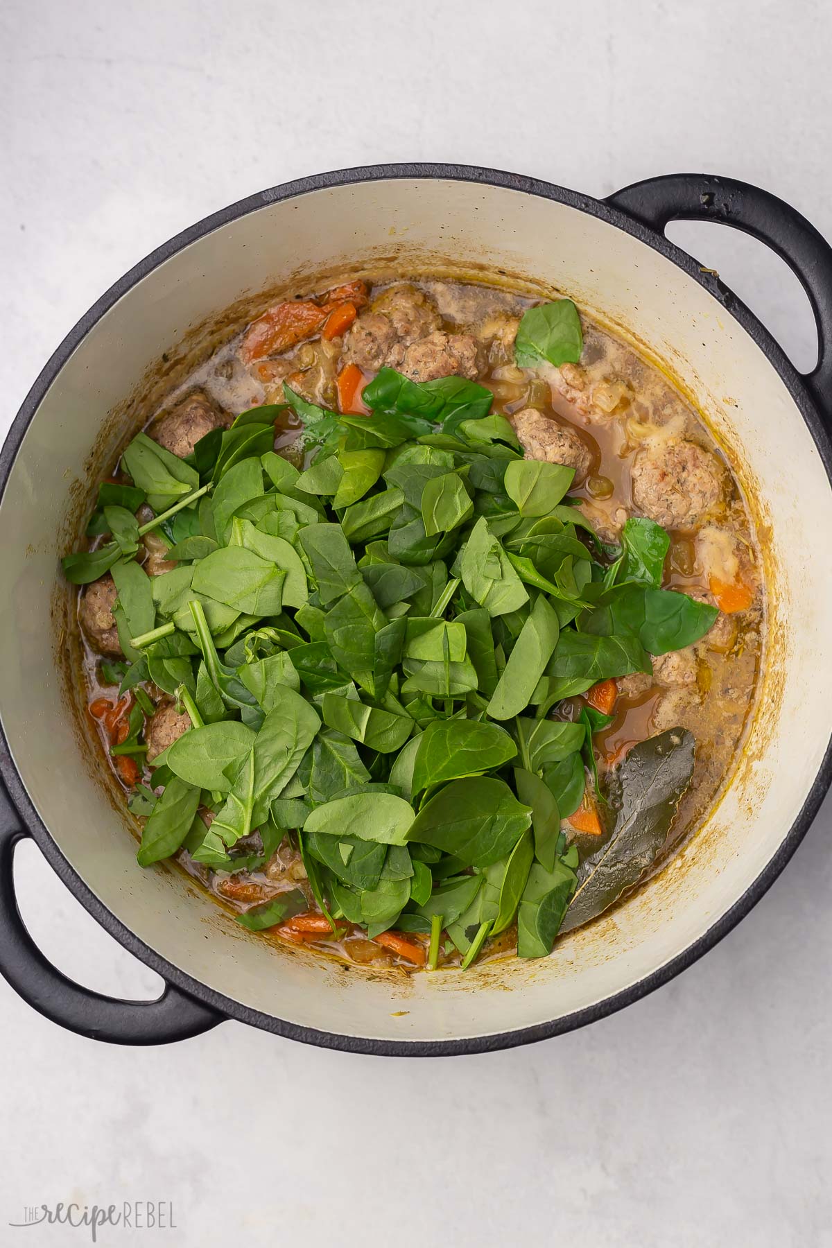 overhead shot of chopped spinach added to soup.