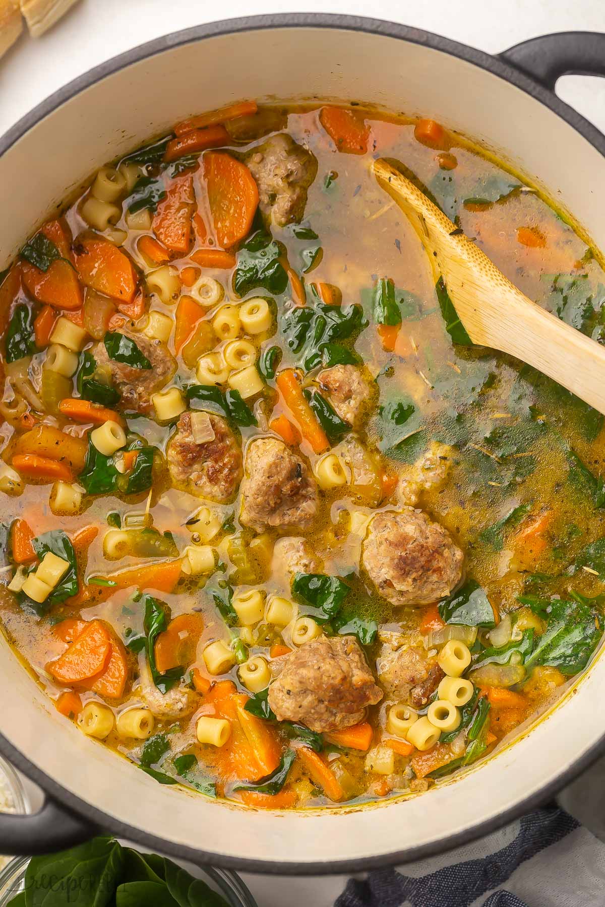 Italian Wedding Soup is loaded with homemade Italian meatballs, pasta, savory vegetables, salty parmesan, and classic Italian seasoning. It's one of our favorite soups for lazy winter days, but it's great for hearty dinners any time of year. #soup #recipe | dinner ideas | dinner recipes | soup recipes | meatball recipe | healthy dinner | easy recipes overhead shot of black dutch oven filled with Italian wedding soup.
