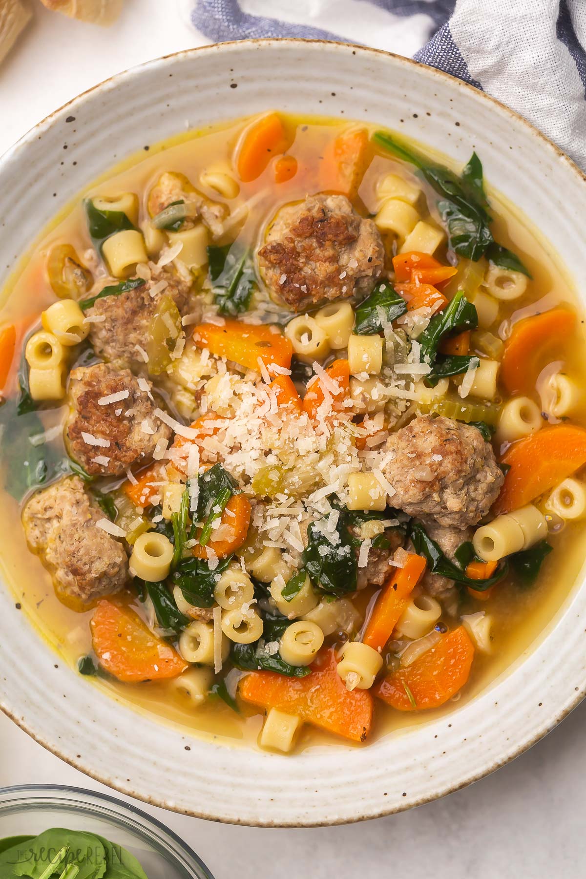 Italian Wedding Soup is loaded with homemade Italian meatballs, pasta, savory vegetables, salty parmesan, and classic Italian seasoning. It's one of our favorite soups for lazy winter days, but it's great for hearty dinners any time of year. #soup #recipe | dinner ideas | dinner recipes | soup recipes | meatball recipe | healthy dinner | easy recipes white bowl filled with soup and topped with parmesan cheese.