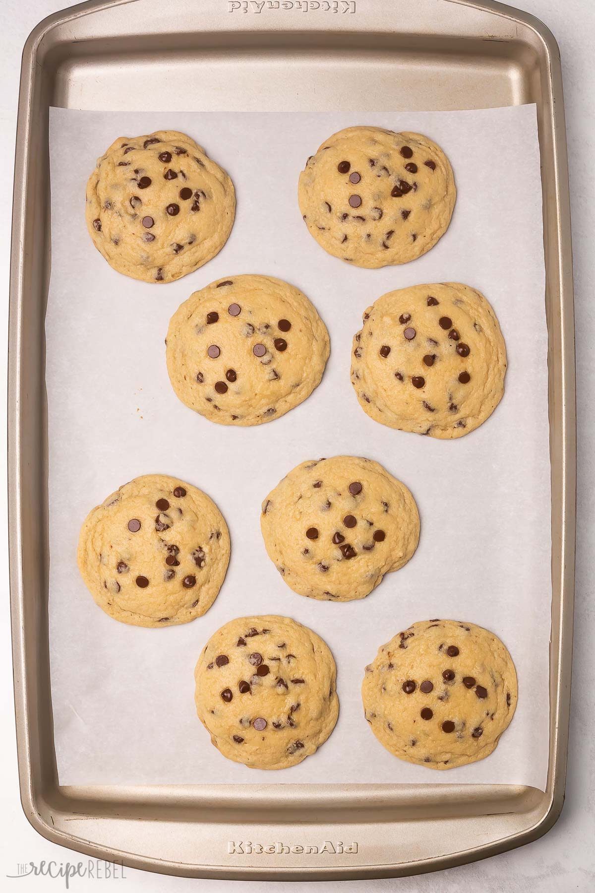 overhead view baking sheet with eight baked chocolate chip cookies.